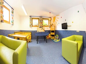 Uma sala de jogos infantil com mesa de futebol de mesa, espaço para brincar e assentos.