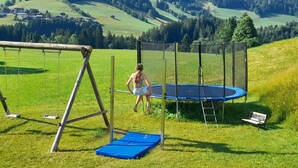 A trampoline set up on a grassy field with a swing set nearby. - Rosskopf by Interhome (Auffach)