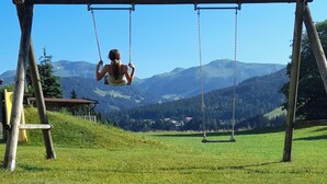 A wooden swing set in a grassy field with a mountain backdrop. - Rosskopf by Interhome (Auffach)