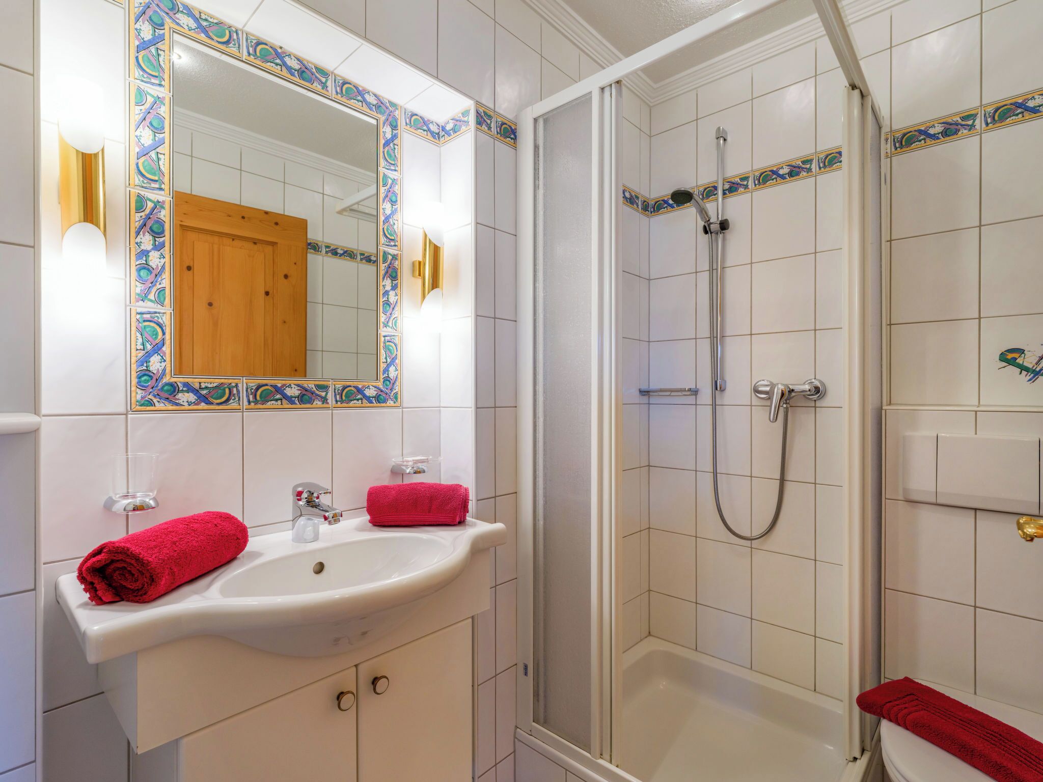 A bathroom with a white sink, mirror, and shower.
