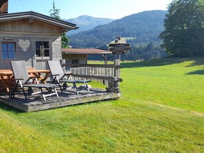 A wooden building with a deck, outdoor seating, and a signpost with destination names. - Gratlspitz by Interhome (Auffach)