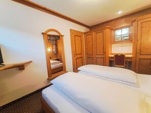 Une chambre à coucher avec un lit, une armoire en bois, un bureau et une fenêtre.