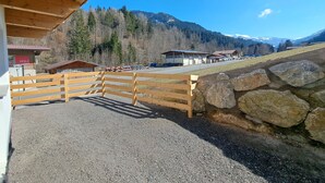 A building with a wooden facade and a gravel driveway leading to a stone wall.