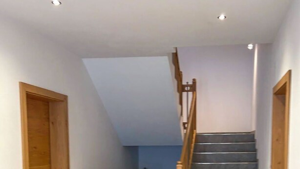 A hallway with a wooden staircase leading to a landing.