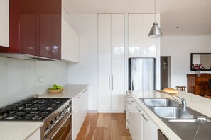 Eine moderne Küche mit weißen Schränken, einer Edelstahl-Spüle und einem Gasherd.