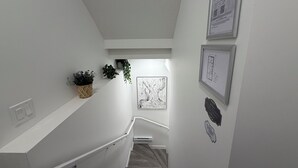 A staircase with a handrail, a wall-mounted plant, and a framed architectural drawing. - Modern Rangeview Stay| Near YMCA & Cineplex Cinema (Calgary)