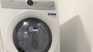 A stacked washer and dryer unit with a control panel and a label indicating 'DRYBOOST' technology. - Modern Rangeview Stay| Near YMCA & Cineplex Cinema (Calgary)
