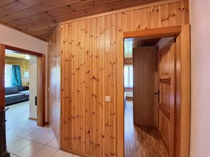 A room with wooden paneling, a tiled floor, and a door leading to another room. - Jägerheim by Interhome (Herbriggen)