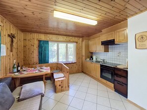 A wooden cabin with a dining area, kitchen, and a cozy seating arrangement. - Jägerheim by Interhome (Herbriggen)