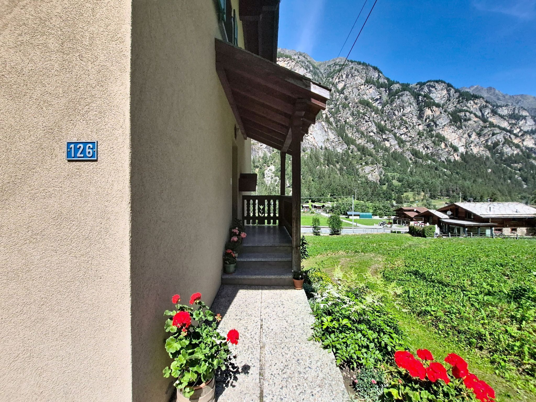 A building with a number '126' sign, a wooden porch, and a mountain view.