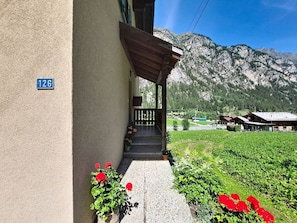 Ein Gebäude mit der Hausnummer 126, einer Holzveranda und Blick auf die Berge.