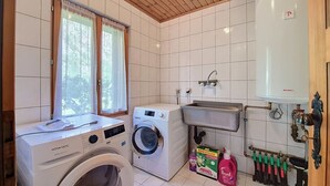Ett tvättrum med tvättmaskin, torktumlare, handfat och varmvattenberedare.