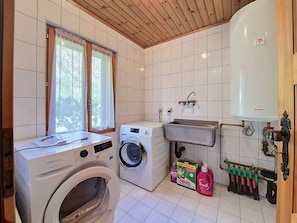Ein Waschraum mit Waschmaschine, Trockner, Spüle und Warmwasserbereiter.