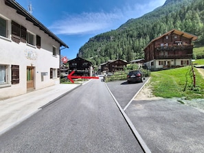 Eine Straße mit Gebäuden, einem Auto und einem Berg im Hintergrund.
