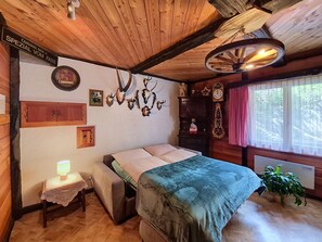 A wooden room with a bed, a small table with a lamp, and a wall adorned with antlers and a clock. - Jägerheim by Interhome (Herbriggen)