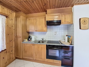 Eine Küche mit Holzausstattung, einer Edelstahl-Spüle, einer schwarzen Dunstabzugshaube und einem eingebauten Backofen.