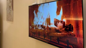 A flat-screen TV mounted on a wall displaying a fireplace scene. - Lying Flat Hostel (Minxiong)