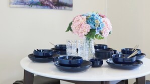 A dining table with multiple blue plates, a vase with pink and blue flowers, and a painting on the wall. - RESIDENTIALHOTELDAIICHI-H OKUBO Room.2C (Tokyo)