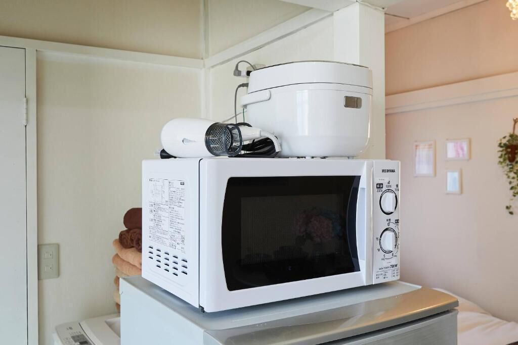 Un forno a microonde posizionato sopra un tostapane, con una cuociriso sopra il forno a microonde.
