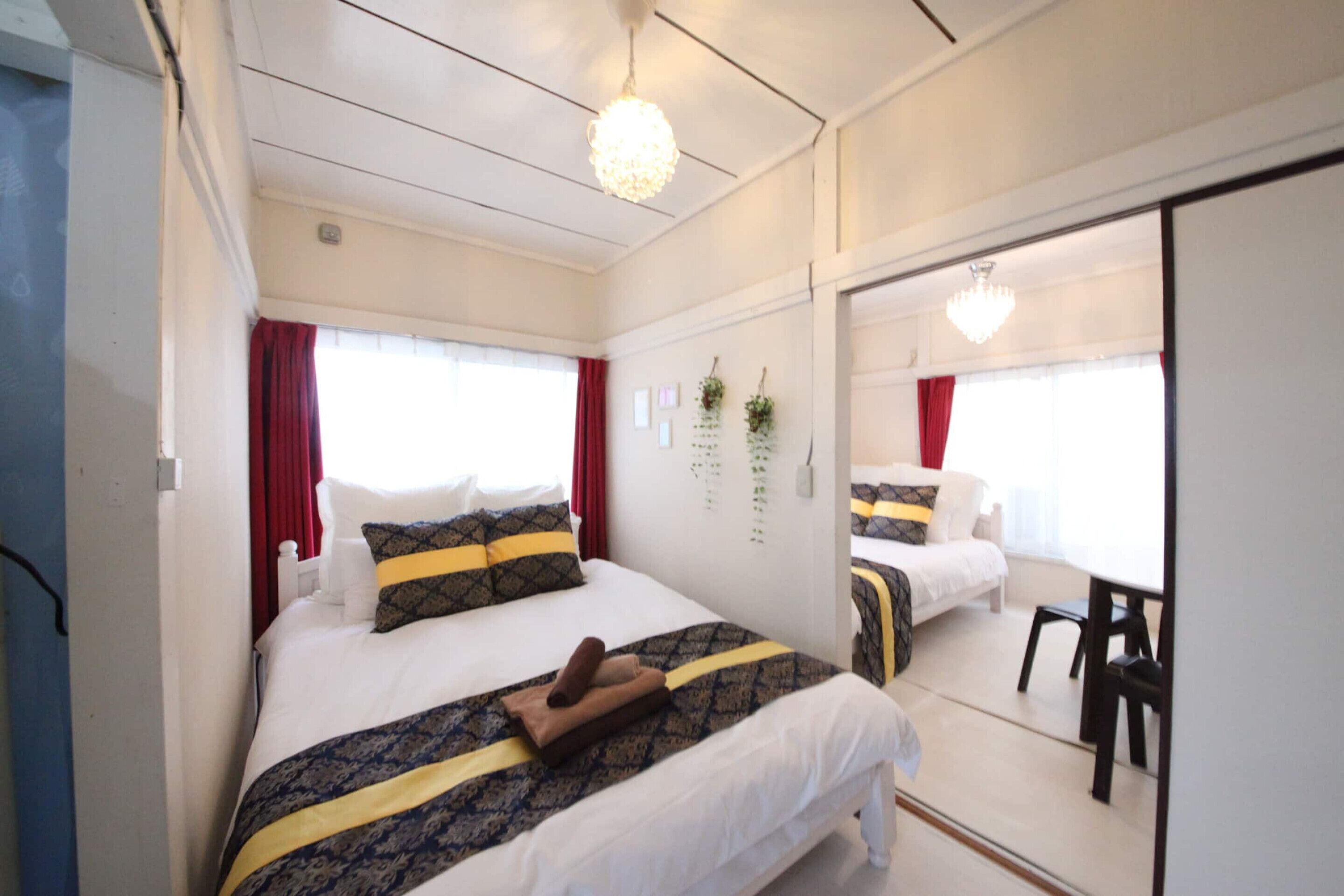 A bedroom with a bed, a mirror, and a window with curtains.