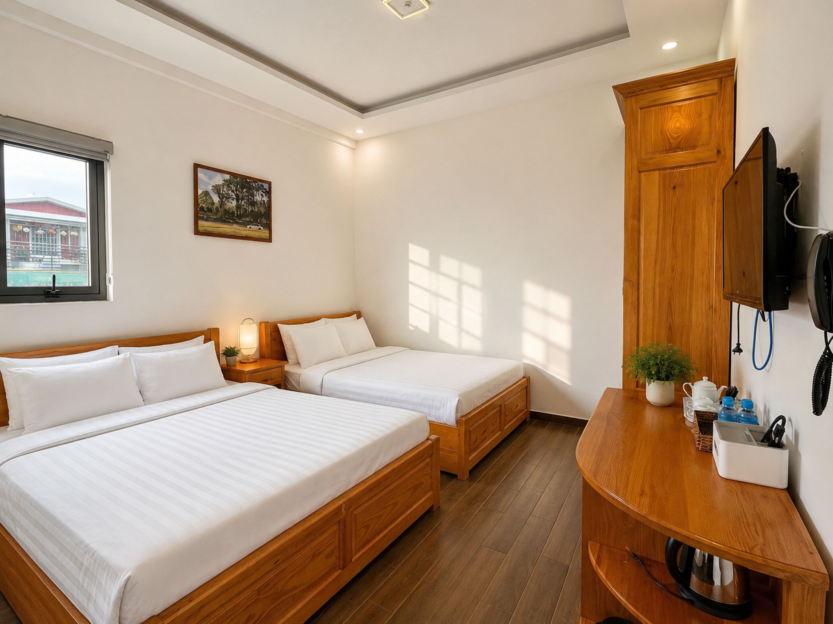 A hotel room with two beds, a wooden cabinet, a TV, and a window with a view of a building.