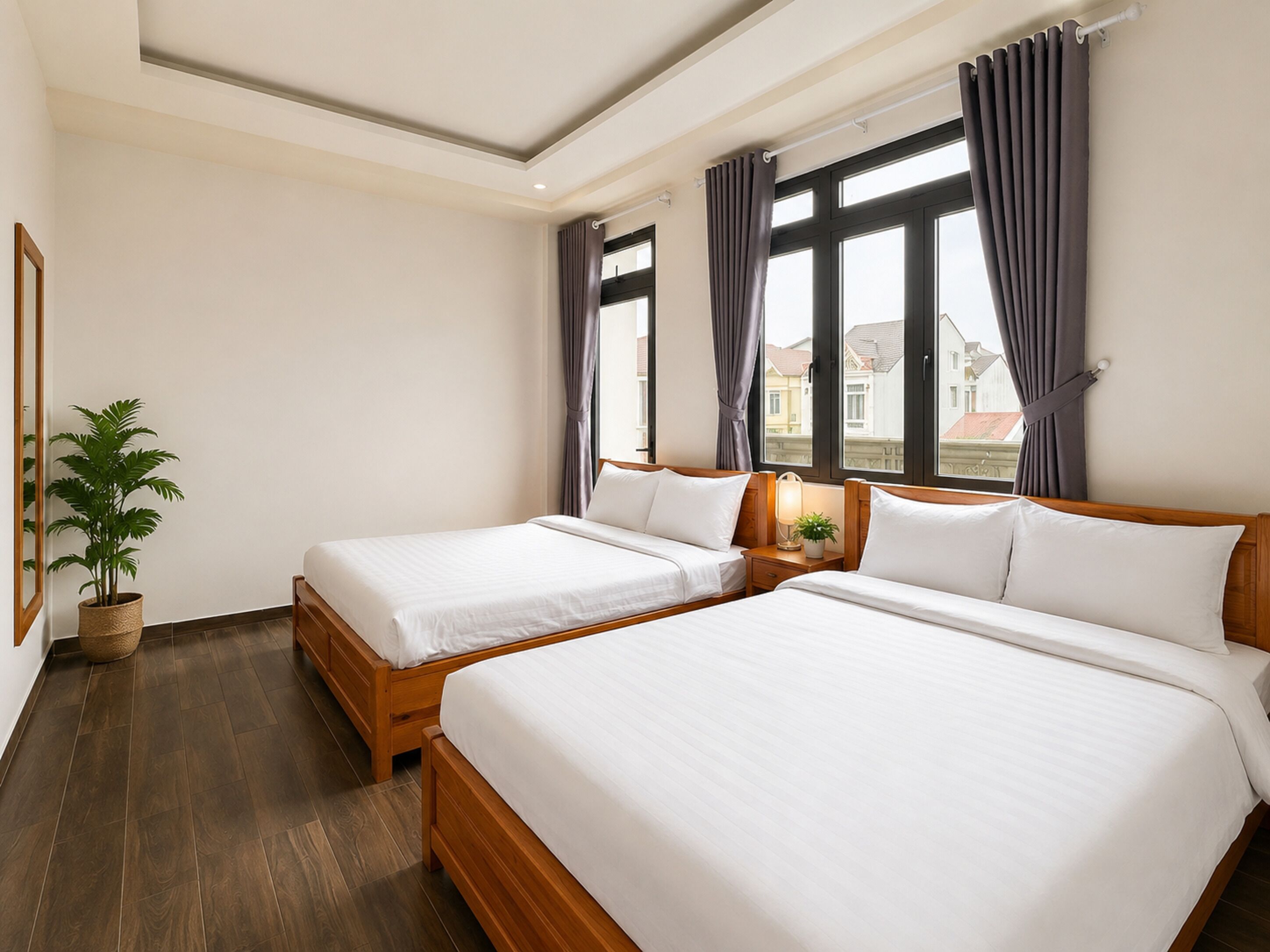 A hotel room with two beds, a potted plant, a nightstand with a lamp, and large windows with curtains.