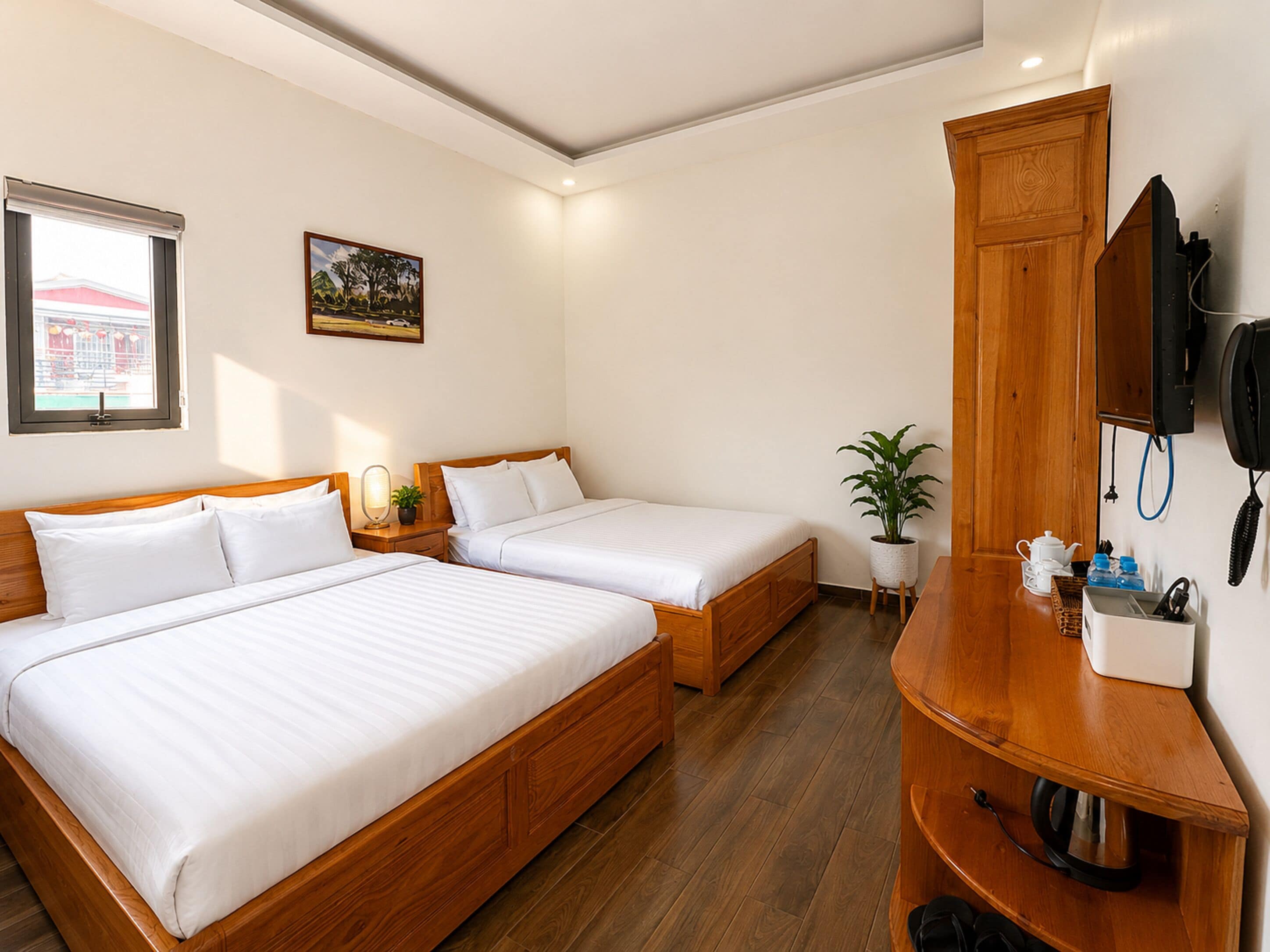 A hotel room with two beds, a wooden cabinet, a potted plant, and a painting on the wall.