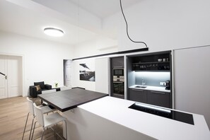 A modern kitchen with a central island, built-in oven, and a dining area with bar stools.