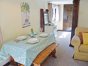 A dining area with a table set for four, a bench, a sofa, and a kitchen area in the background. - Walnut Tree - UK52235 (Horning)