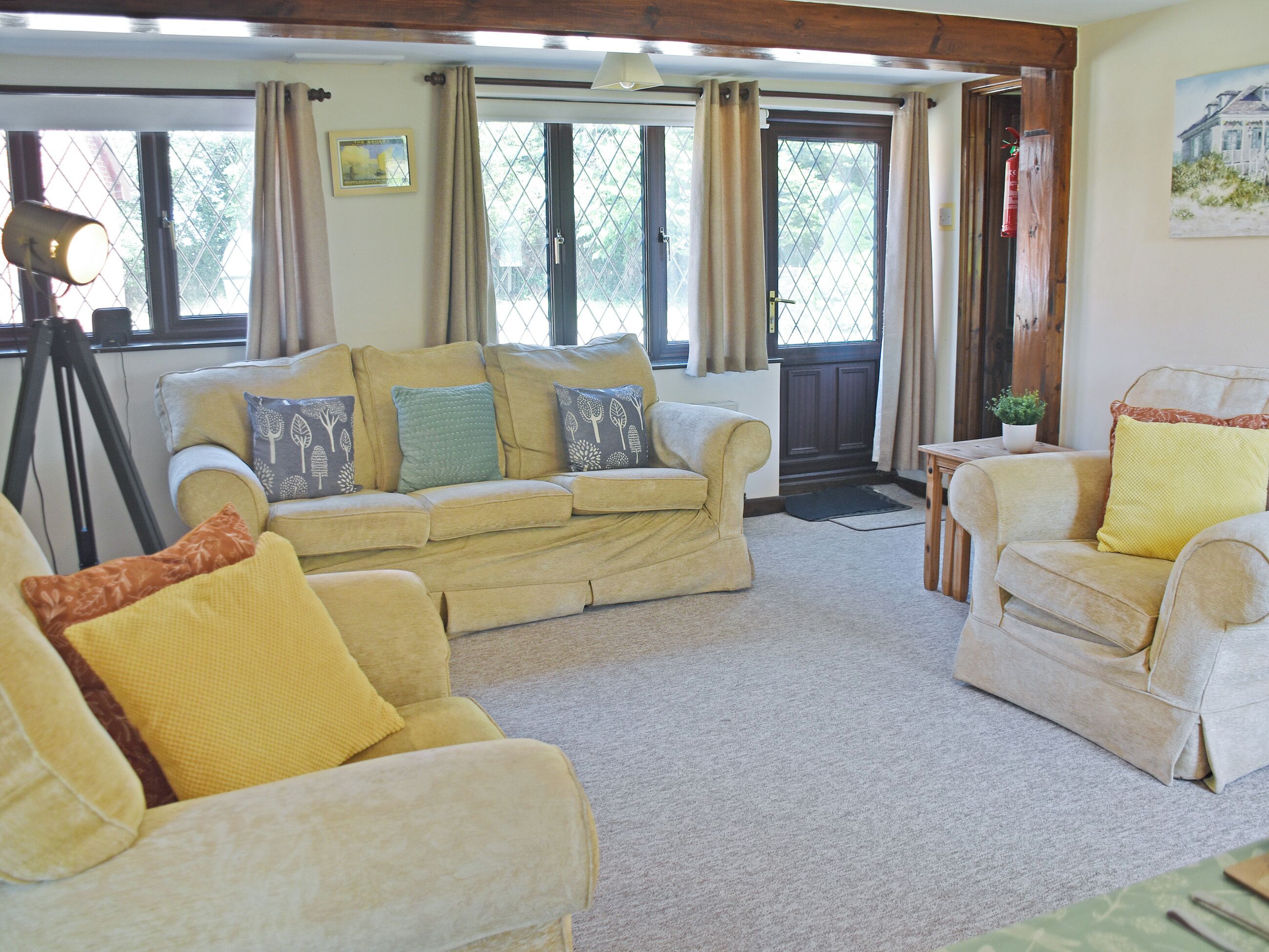 A living room with a sofa, armchairs, and a small table with a plant.