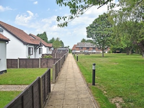 Un camino que conduce a una zona residencial con casas, una mesa de picnic y un campo cubierto de césped.