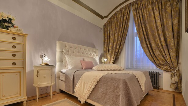 Ein Schlafzimmer mit einem großen Bett, einem Nachttisch, einer Kommode und einem Fenster mit Vorhängen.