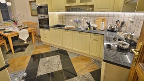 Eine Küche mit Essbereich, ausgestattet mit einer Arbeitsplatte aus Granit, einem Backofen und verschiedenen Küchenutensilien.