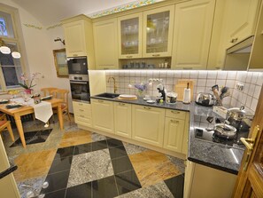 A kitchen with a dining area, featuring a granite countertop, a built-in oven, and a variety of kitchen utensils. - Apartment Dalia by Interhome (Smichov Kosire Jinonice)
