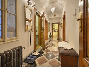 A hallway with a radiator, a bench, a door with a mirror, and a chandelier. - Apartment Dalia by Interhome (Smichov Kosire Jinonice)