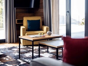 Ein modernes Wohnzimmer mit einer Couch, einem Couchtisch, einem Sessel und einem Fernseher.