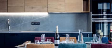 Une cuisine moderne avec des meubles en bois, un évier en acier inoxydable et un coin repas avec une table dressée pour deux personnes.