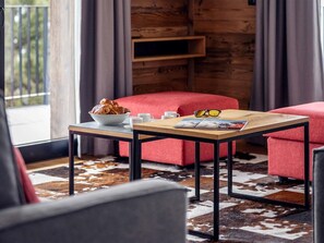 A modern living room with a wooden table, red sofa, and a cowhide rug.