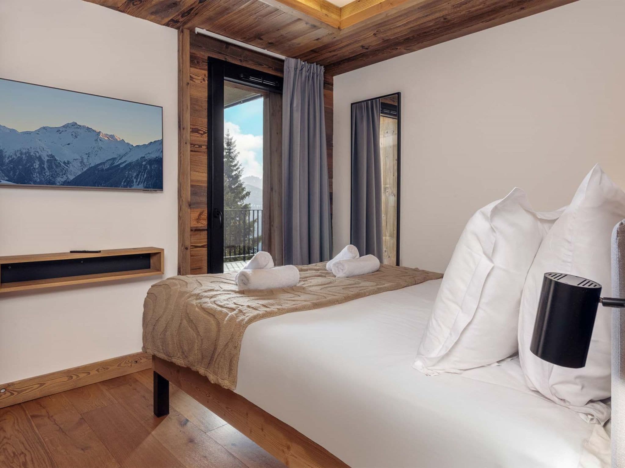 Une chambre à coucher avec un lit, un plafond en bois, une fenêtre avec des rideaux, un tableau accroché au mur et une table de chevet.