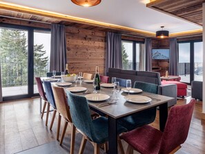 A dining area with a wooden table set for six, surrounded by chairs with various textures.