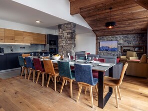Eine moderne Küche mit Steinwand, Holzboden und einem Essbereich mit bunten Stühlen sowie einem Flachbildfernseher.