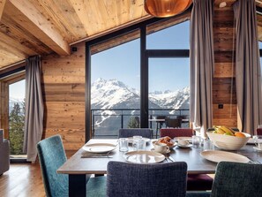 Ein Essbereich mit Tisch für vier Personen, Blick auf die Berge und Holzwände.