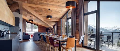 Een moderne keuken met een lange aanrecht, houten kastjes en een groot raam met uitzicht op een bergachtig landschap.