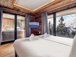 A hotel room with a large bed, a television mounted on the wall, and a view of a snowy mountain landscape. - Résidence l'Orée du Bois by Interhome (La Rosière)