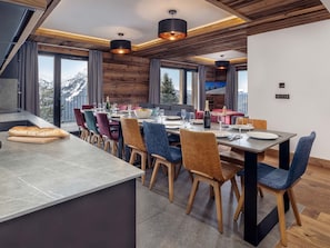 A modern dining area with a long table, colorful chairs, and a view of mountains. - Résidence l'Orée du Bois by Interhome (La Rosière)