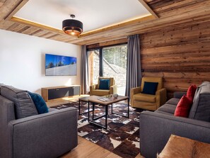 A modern living room with a stone wall, wooden ceiling, and large windows. - Résidence l'Orée du Bois by Interhome (La Rosière)