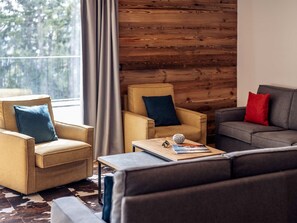 Una sala acogedora con un sofá, un sillón y una mesa de centro con un globo terráqueo y gafas de sol.