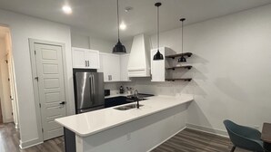 A modern kitchen with a central island, stainless steel appliances, white cabinetry, and pendant lighting. - Newly Built Home 7 Min Drive River Walk & Downtown - 1222 (San Antonio)