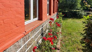 A red brick building with white-framed windows and a garden with red flowers. - "Helge" - 10km from the sea by Interhome (Rønne)