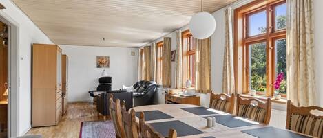 A spacious room with a large table, chairs, a sofa, and a wardrobe.